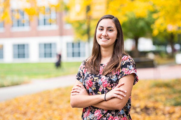 A student stands outside smiling