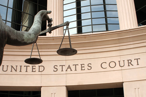 A statue holding scales outside of a court building