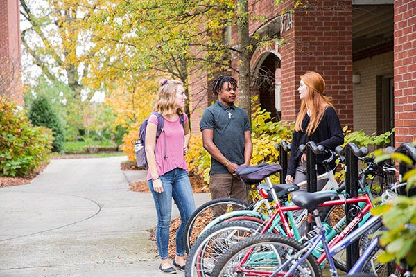 Three students standing outside and talking to one another