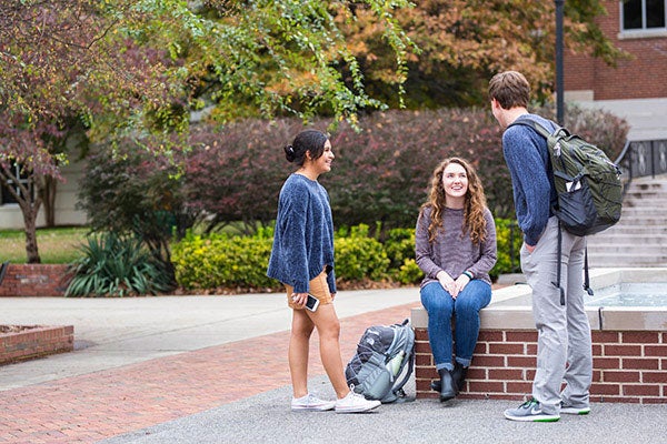 Three students stand outside talking