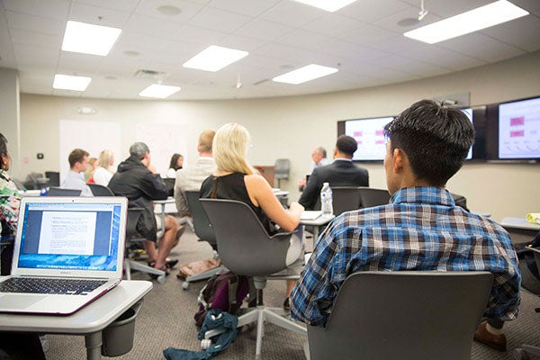 A classroom of business students listen in to a lecture by a professor