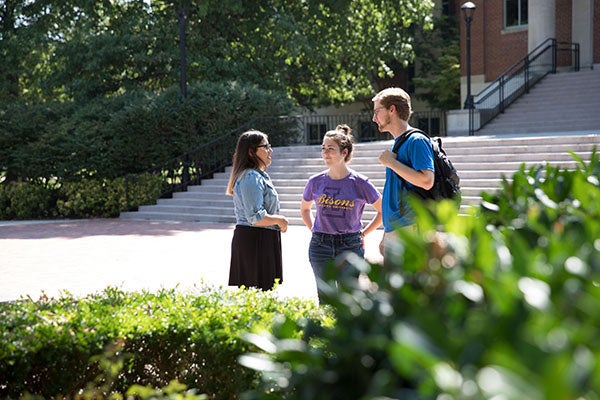 Three students standing outside and talking