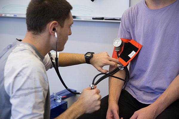 One student takes the blood pressure of another student