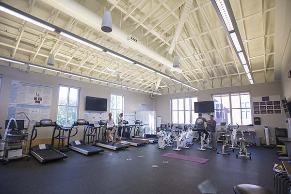 Four students complete different activities in the weight room