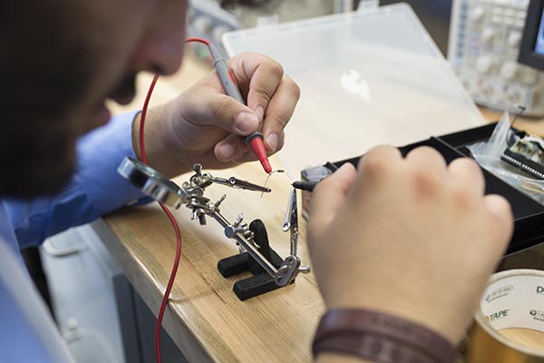 A student uses a variety of tools to build a circuit