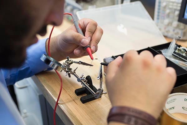 A student uses a variety of tools to build a circuit