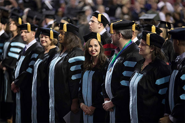 A cohort of doctorate of education students stand at graduation