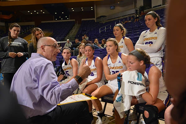 A coach talks to eight of his athletes in the middle of a timeout