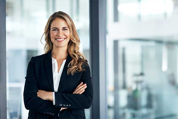 Woman standing against glass wall in professional attire.