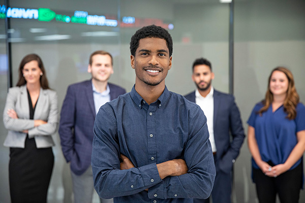 Five fast track MBA students standing together with one in the forefront in the College of Business building.