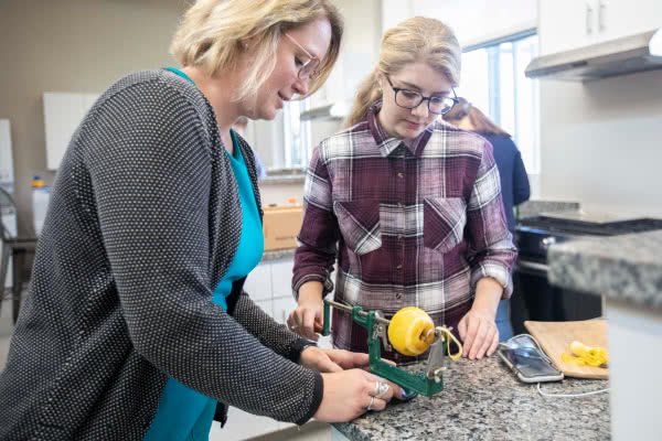 Students peel an apple in a test kitchen