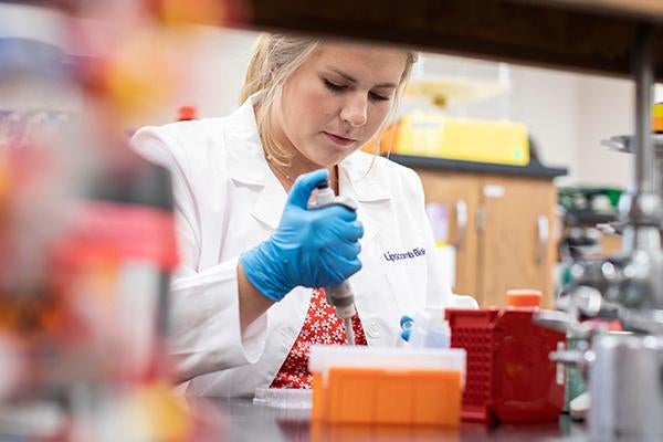 Student in a white coat working in a lab