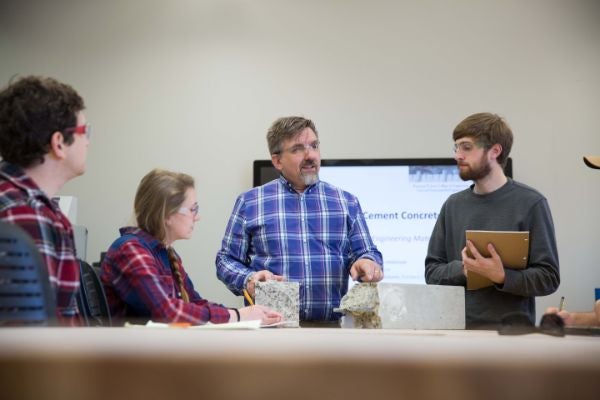 students talking with professor while he is giving a presentation on concrete 