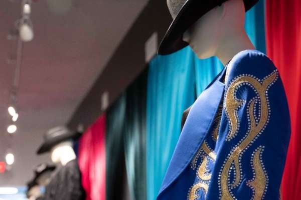 a mannequin wearing a jeweled blue jacket and black hat 