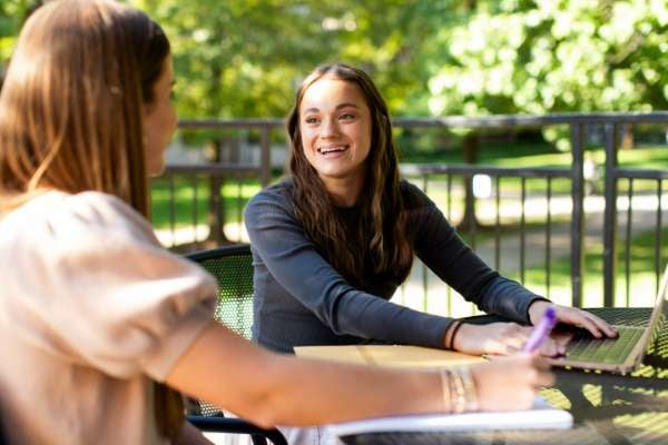 Two students stand outside talking
