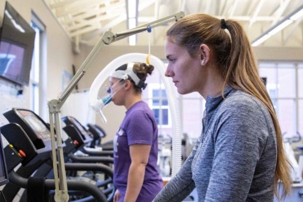 A woman and a man ride exercise bikes in a fitness room