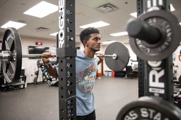 student at the gym lifting weights