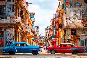 View of a street in Cuba with two cars in foreground.