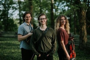 Two men and one women standing in the woods