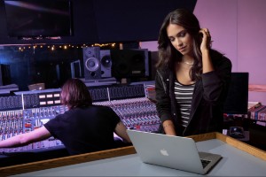 Female singer in a music studio standing in front of a computer