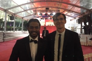 Two students in suits standing on the red carpet at Cannes.