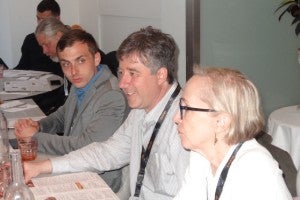 Three people sitting at table in discussion. 