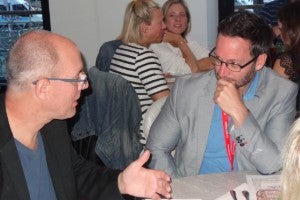 Two men sitting at table talking. 