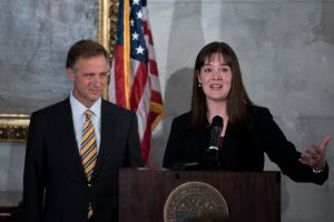 Candice McQueen speaking at a podium with former Tennessee Gov. Bill Haslam
