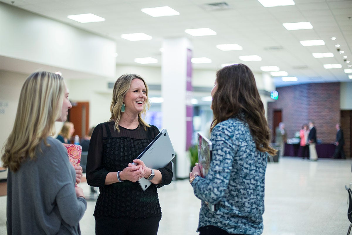 Business faculty member speaks to students between classes