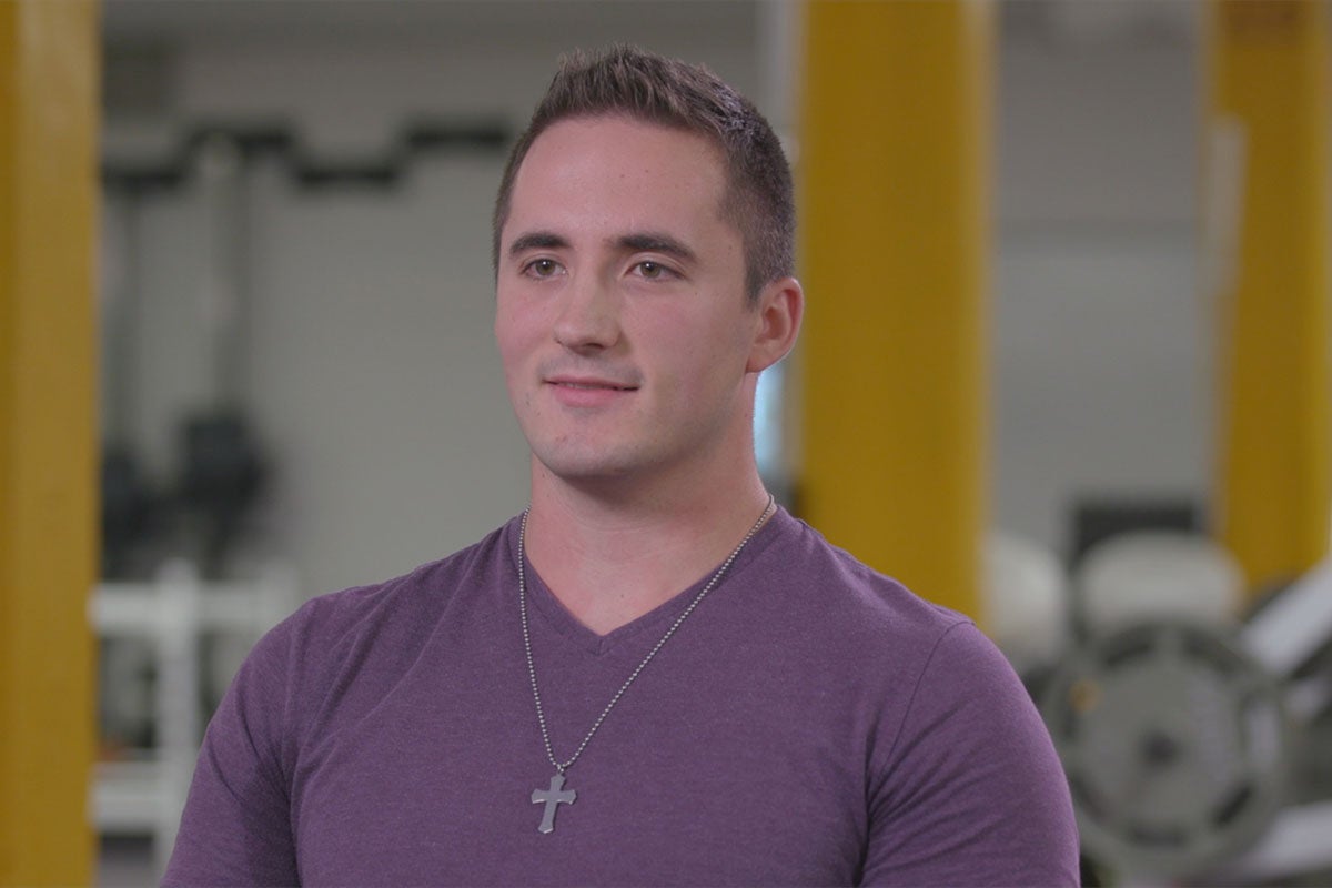 Hayden Hall seated with exercise equipment in the background.