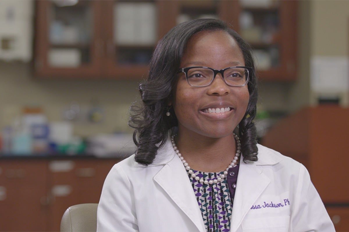 Klarissa Jackson in lab coat sitting in a lab on Lipscomb's campus.