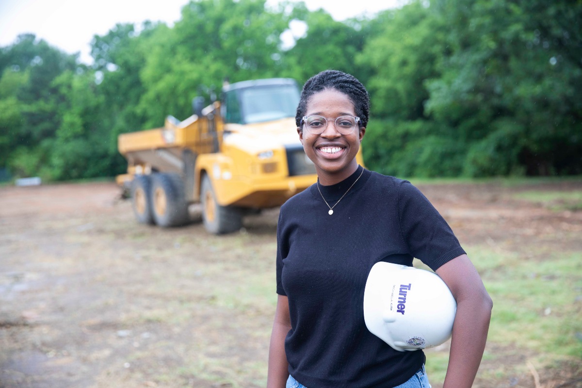 Michaela Kirk standing in front of a construction vehicle