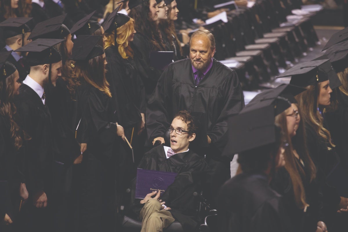 Seth Walker and Ken Brassell walk back to their seats after receiving diplomas