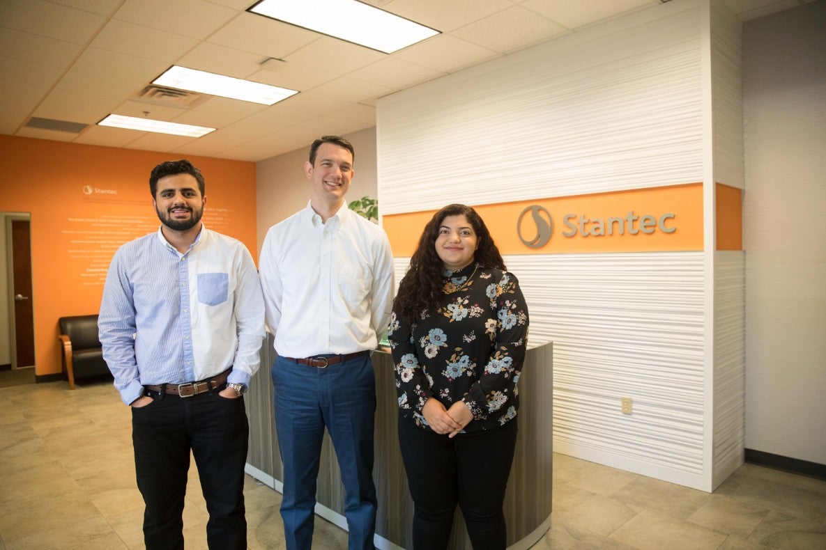 Three people standing in the lobby of an engineering firm.