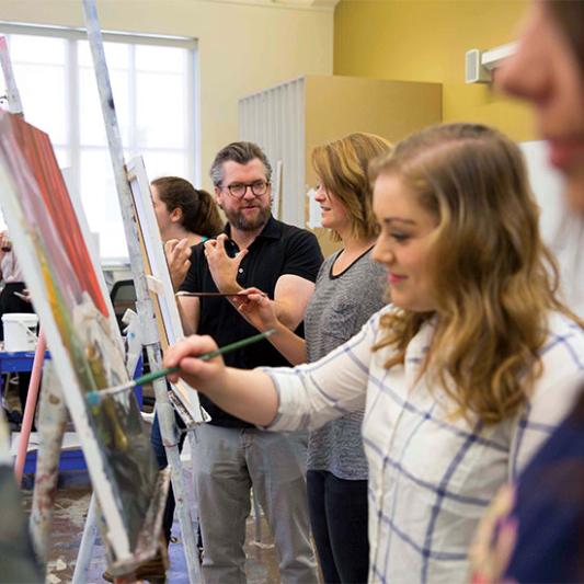 Art professor instructs students on painting techniques.