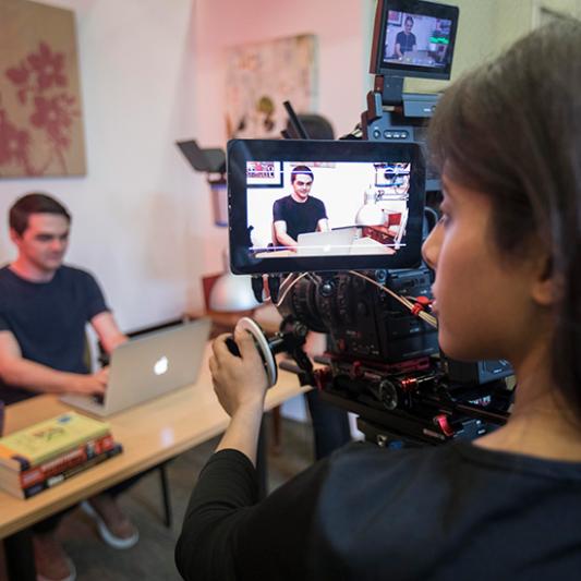 A student with a video camera films another student