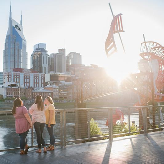 Students walk alongside the Cumberland River and the Nashville skyline.