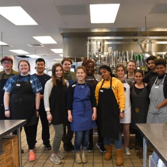 Students cooking in the kitchen with the staff