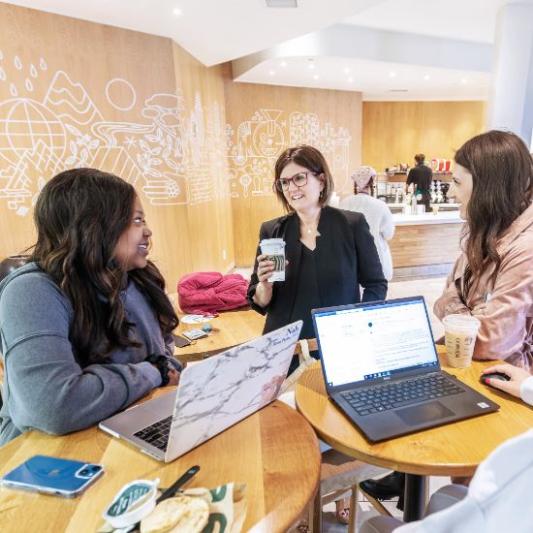 Two students meeting with their professor at Starbucks