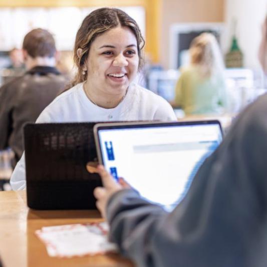 A girl facing the screen working with another student.