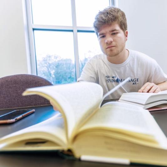 Student studying with a book open in front of him
