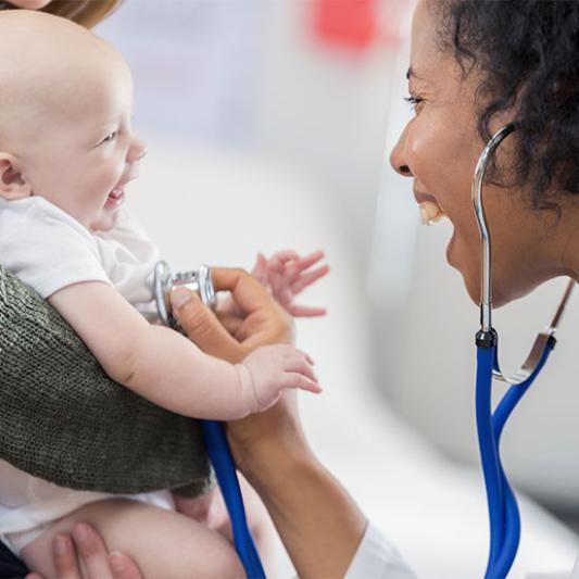 Nurse uses stethoscope on a laughing baby.