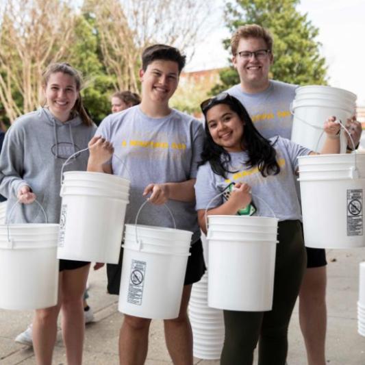 A group of student volunteers holding buckets