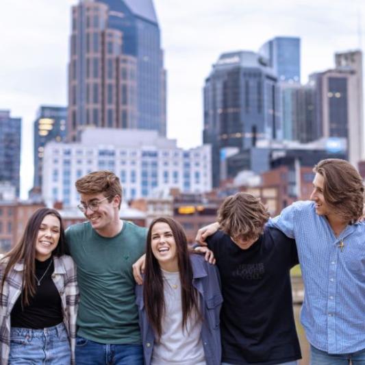 Students smiling and standing in front of the Nashville skyline