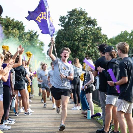 Students running with Lipscomb flag