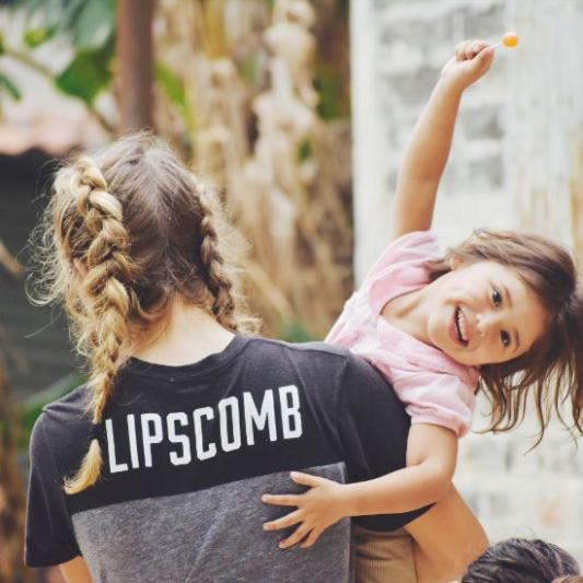 child smiling while being help by a missions student