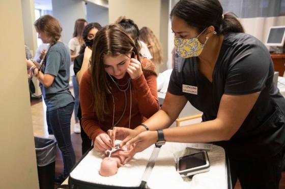 Summer Scholars student listens to heartbeat on preemie patient simulator