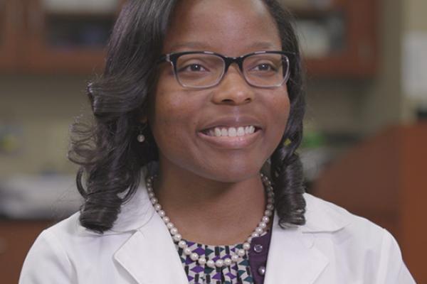 Klarissa Jackson in lab coat sitting in a lab on Lipscomb's campus.