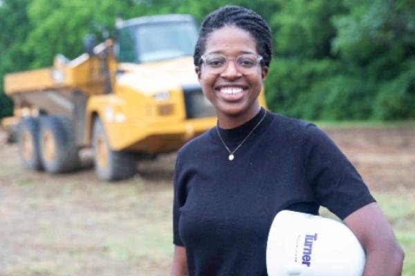 Michaela Kirk standing in front of a construction vehicle