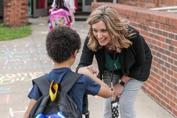 Dr. Jean Luna-Vedder greeting students at school